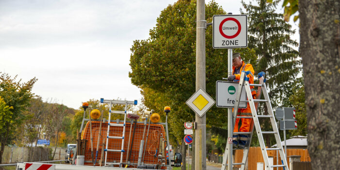 Foto: Rückbau der Umweltzone © Stadtverwaltung Erfurt Ein Mann steht auf einer Leiter und demontiert Verkehrsschilder, die die Umweltzone ausweisen.