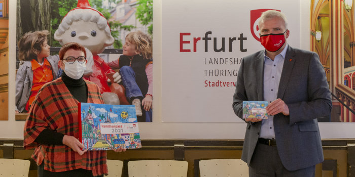Foto: Vorstellung Familienpass © Stadtverwaltung Erfurt Zwei Personen stehen nebeneinander und halten eine Broschüre mit dem Titel "Familienpass 2021"