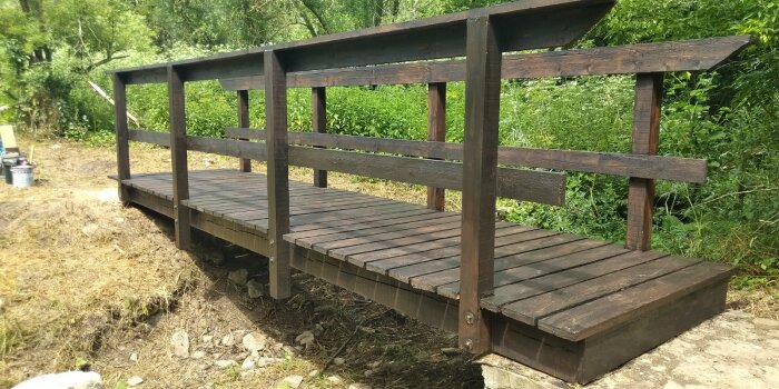 eine Holzbrücke, die über einen trockenen Bachlauf führt