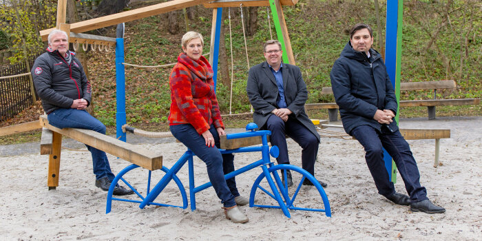 vier Personen sitzen auf einem Spielplatz