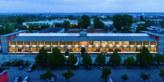Foto: Das Kontor - Zentrum für Kreativwirtschaft © Kontor Eine Nachtaufnahme von einem beleuchteten länglichen Gebäude