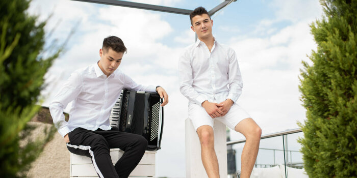 Foto: Akkordeon-Duo Contrust © Contrust zwei sitzende junge Männer, neben einem von ihnen steht ein Akkordeon