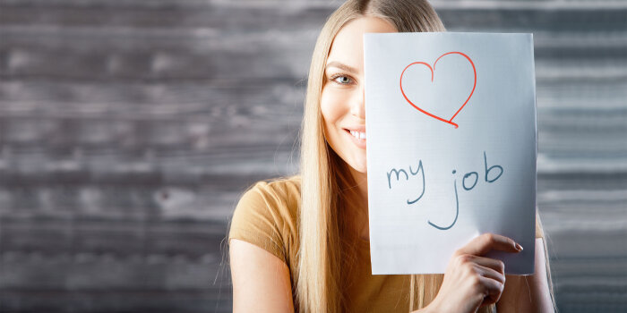 Eine Frau hält ein Blatt Papier in der Hand mit der Aufschrift: "Love my Job"