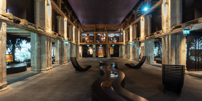 ein Ausstellungsraum mit verschiedenen multimedialen Inszenierungen und Säulen im Innenraum einer alten Kirche