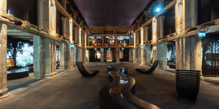 Foto: „Paradiesgärten – Gartenparadiese“ in der Erfurter Peterskirche © Stiftung Thüringer Schlösser und Gärten / Philipp Hort ein Ausstellungsraum mit verschiedenen multimedialen Inszenierungen und Säulen im Innenraum einer alten Kirche