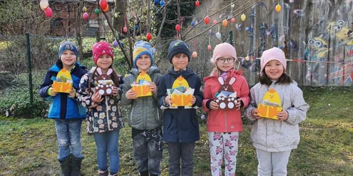 Fünf Kinder stehen nebeneinander und halten Osterkörbchen in ihren Händen.