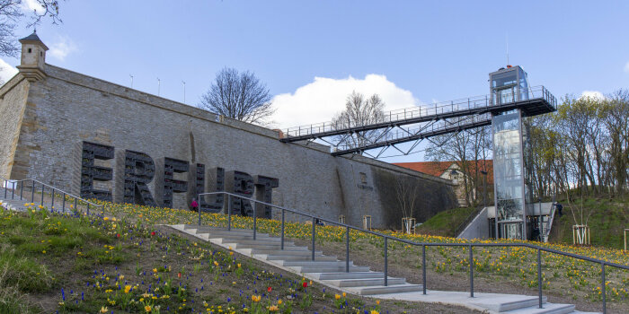 Eine Treppe führt zu einer Bastionsmauer,rechts und links sind Blumen.