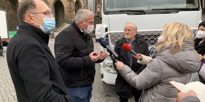 Foto: Pressekonferenz zum Weihnachtsmarkt © Stadtverwaltung Erfurt Mehrere Personen stehen vor einem LKW. Ein Mann spricht in zwei Mikrofone.