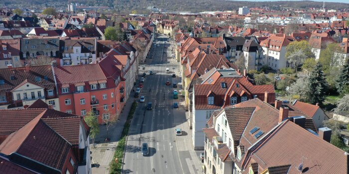 Eine vierspurige Hauptverkehrsstraße aus der Luft aufgenommen. Rechts und links sind große Häuser.