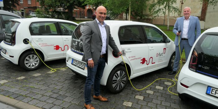 zwei Männer stehen vor einem Elektroauto