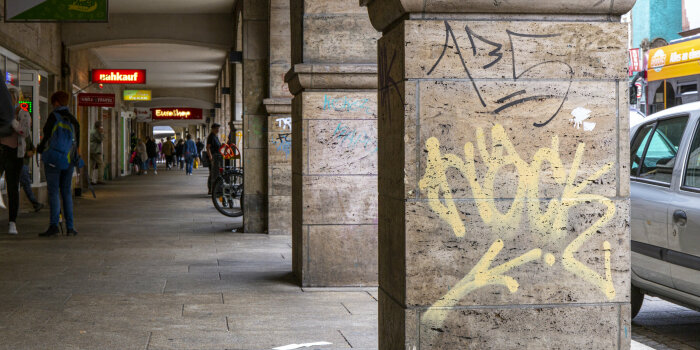 eine von Säulen gesäumte Passage, auf den Säulen sind Graffiti und Schmierereien zu sehen