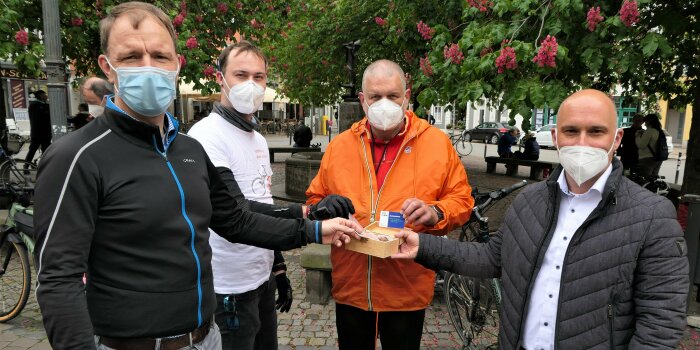 Vier Männer stehen nebeneinander auf einem Platz.