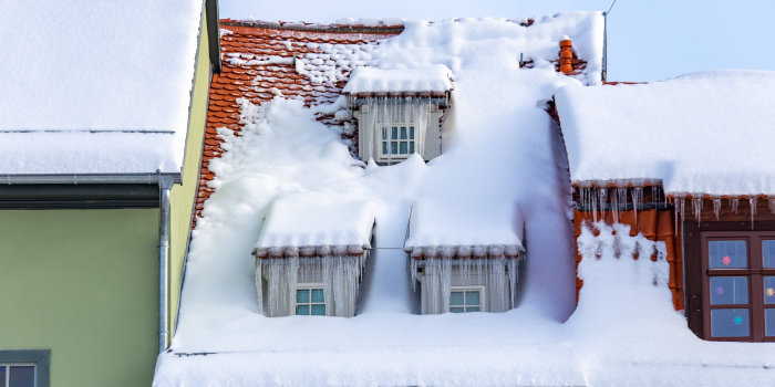 eine Dachgeschoss eines Hauses mit drei Fenstern, an denen Eiszapfen hängen