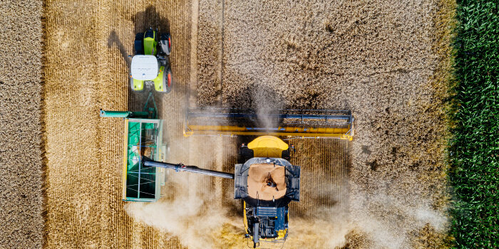 Luftaufnahme eines Mähdreschers und Traktors bei der Ernte