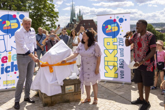 zwei Menschen stehen neben einem verhüllten Gegenstand