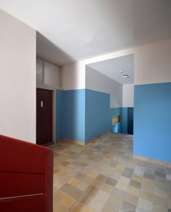 Ein Hausflur mit blauen Wänden und roten Türen