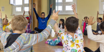 Kinder beteiligen sich an Übungen mit einem männlichen Trainer.