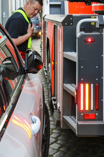 Ein Feuerwehrfahrzeug fährt nur wenige Zentimeter an einem falsch geparkten Auto vorbei.