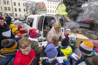 Zwei Frauen und zahlreiche Kinder packen Geschenke in einem Kofferraum.