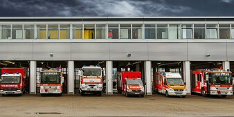 sechs verschiedene Feuerwehrfahrzeuge stehen in ihren Garagen auf einer Feuerwache