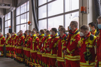 Feuerwehrleute stehen nebeneinander vor einer Glasfront.