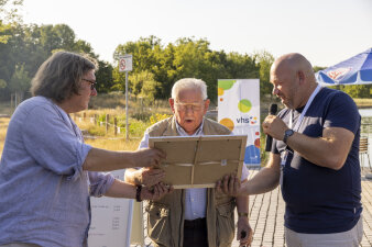 ein Mann bekommt von zwei Männern ein gerahmtes Bild überreicht