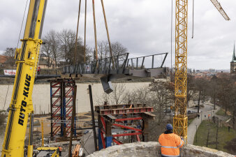 auf der Baustelle: an einem Kran hängt ein Stahlteil