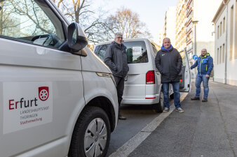 drei Männer stehen an zwei Kleinbussen