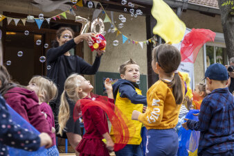 Eine Frau bedient eine Seifenblasenmaschine. Kinder freuen sich darüber. 