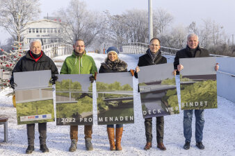 Fünf Personen stehen auf einer Brücke und halten große Tafeln in den Händen.