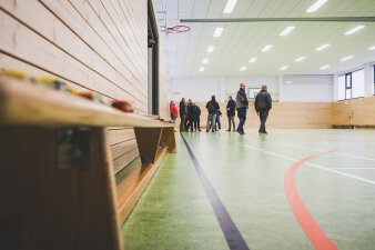 Mehrere Menschen stehen in einer Turnhalle