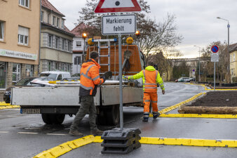 Zwei Männer in Arbeitskleidung räumen Verkehrsbaken auf einen Transporter.