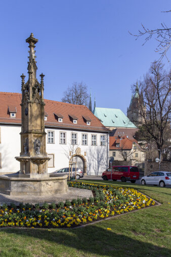 ein Blumenbeet rund um einen steinernen Brunnen 