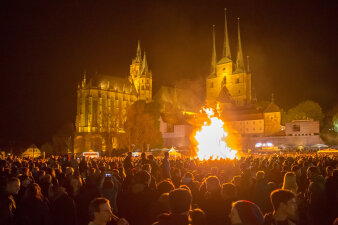 Viele Menschen, die um ein Feuer stehen, dahinter der Dom