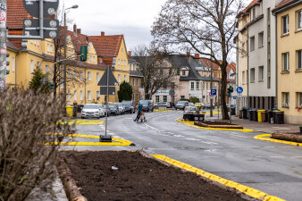 Zwei Erwachsene und ein Kind überqueren eine Straße nach deren Umgestaltung.