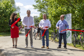 vier Menschen durchschneiden ein rotes Band