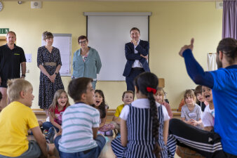 Kinder beteiligen sich an Übungen. Erwachsene schauen dabei zu. 