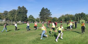 Eine Gruppe von Kindern bewegt sich auf einer Wiese durch einen Parcours.