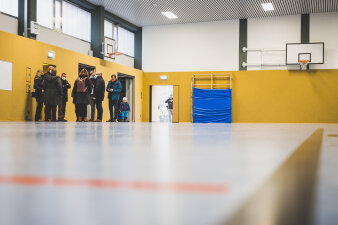 Mehrere Menschen stehen in einer Turnhalle