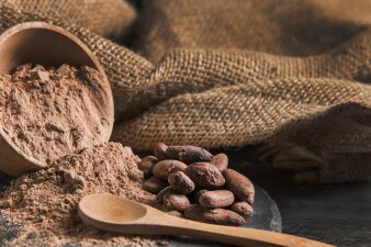 Kakaopulver und Bohnen mit einem Holzlöffel