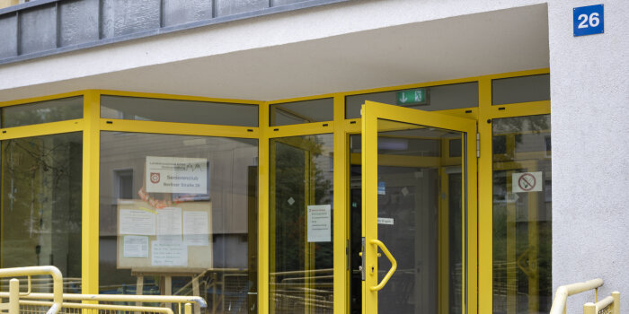 Sommertour 2022 Seniorenclub Berliner Straße Der Eingangsbereich in ein Gebäude mit auffällig gelbem Türrahmen.