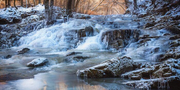 Ein Fluss fließt durch eine Winterlandschaft.