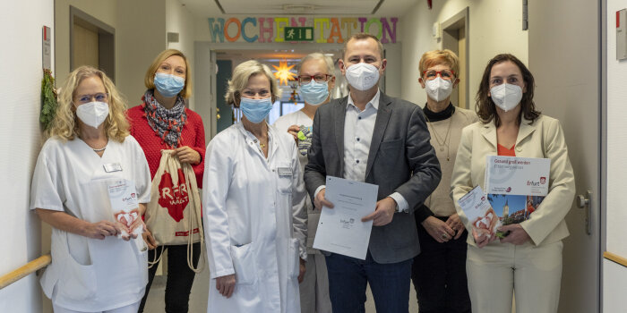 Sechs Frauen und ein Mann stehen beisammen und halten Flyer, Beutel und Zettel in der Hand.