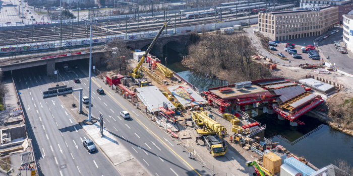 Foto: Einhub der Brückenteile für das Promenadendeck © Stadtverwaltung Erfurt Eine Luftaufnahme von einer breiten Straße, über der eine neue Brücke entsteht.