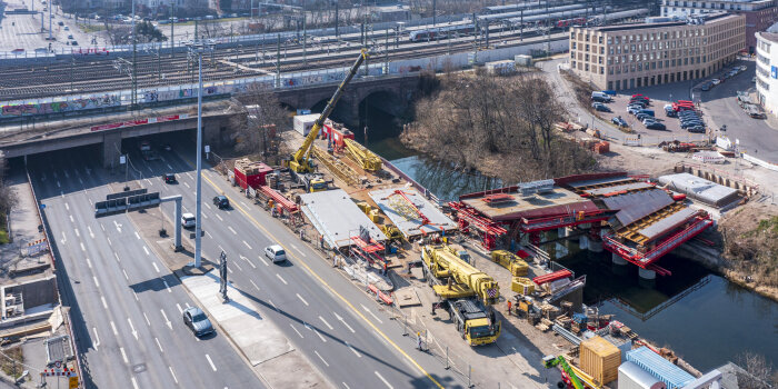 Eine Luftaufnahme von einer breiten Straße, über der eine neue Brücke entsteht.