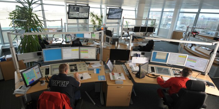 Foto: Blick in die Leitstelle der Berufsfeuerwehr Erfurt © Stadtverwaltung Erfurt Viele Monitore, Telefone und Bildschirme, an zwei Schreibtischen sitzen zwei Personen mit Headset