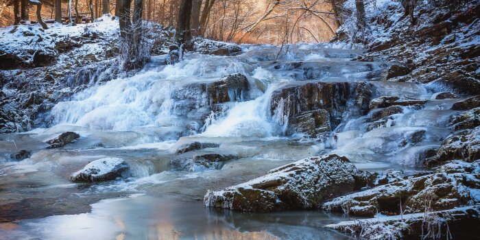 Ein Fluss fließt durch eine Winterlandschaft.