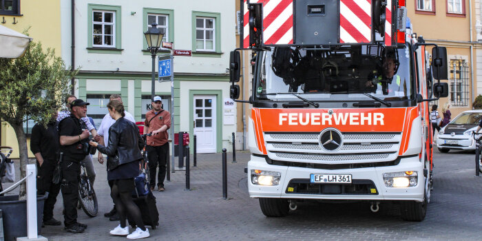 Ein Feuerwehrfahrzeug fährt über einen belebten Platz.