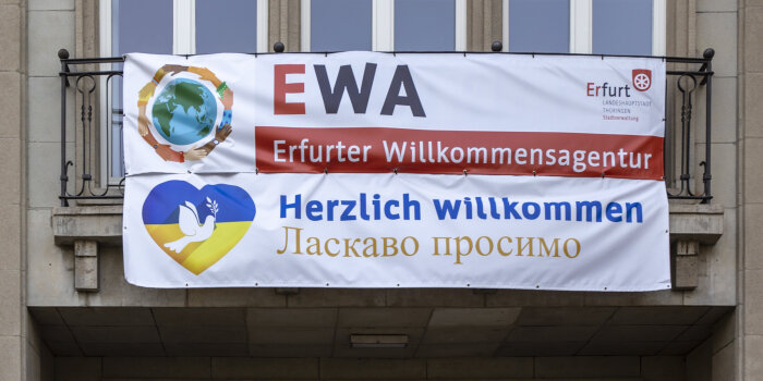 ein Banner mit dem Schriftzug "Ewa Erfurter Willkommensagentur" hängt an einem Gebäude