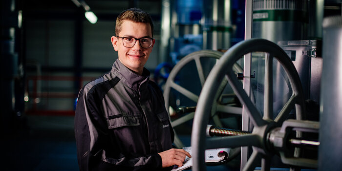 Foto: Auszubildender der Stadtwerke Erfurt Gruppe © SWE Stadtwerke Erfurt GmbH ein junger Mann in Arbeitskleidung steht an einem Maschinenrad